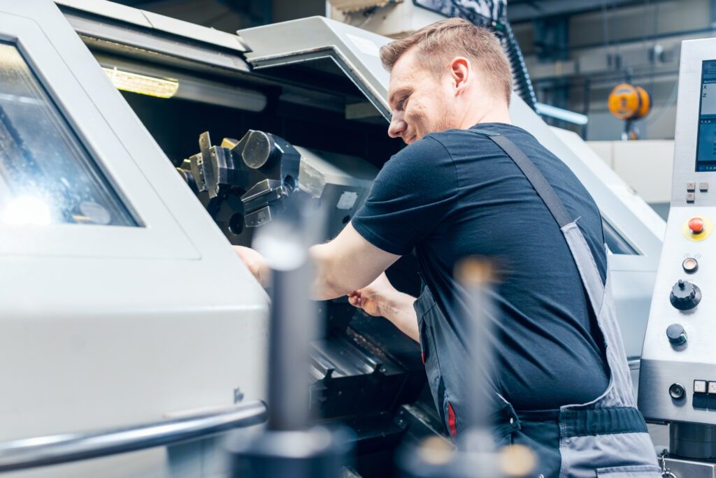 Experienced worker changing tool setup of lathe machine on the factory floor